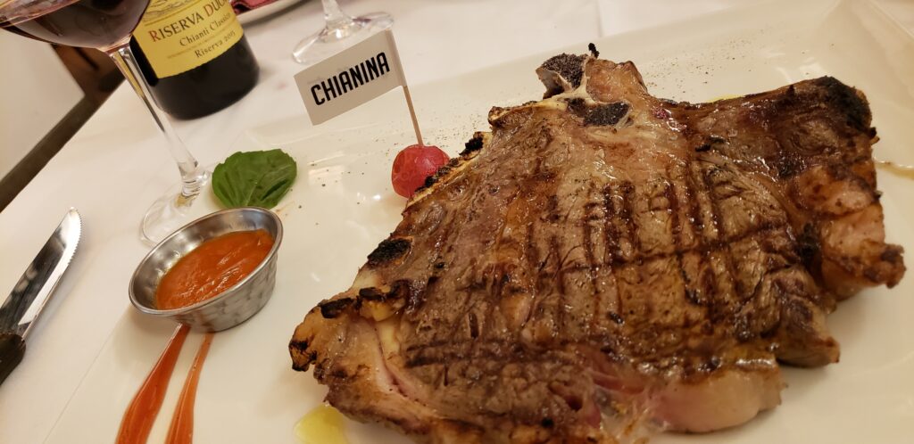 Florentine Steak on a plate with a "Chianina" flag in a cherry tomato for decorative plating.