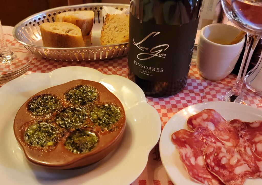 appetizers of six baked escargot, bread, wine, and ham in Paris restaurant