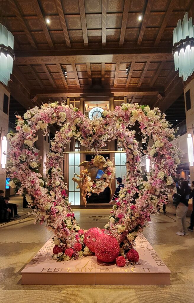 Large heart-shaped decoration with flowers and angels in a hotel lobby.