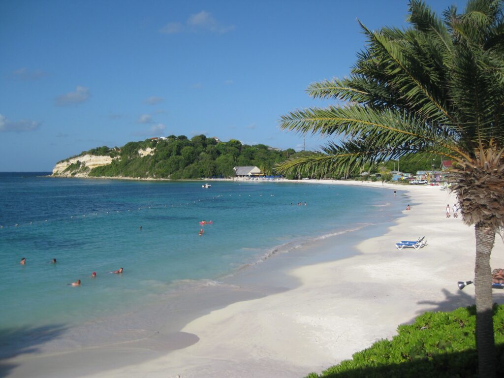 People swimming at the beach at Pineapple Beach Club in Antigua that has white sand and is a great beach for swimming.