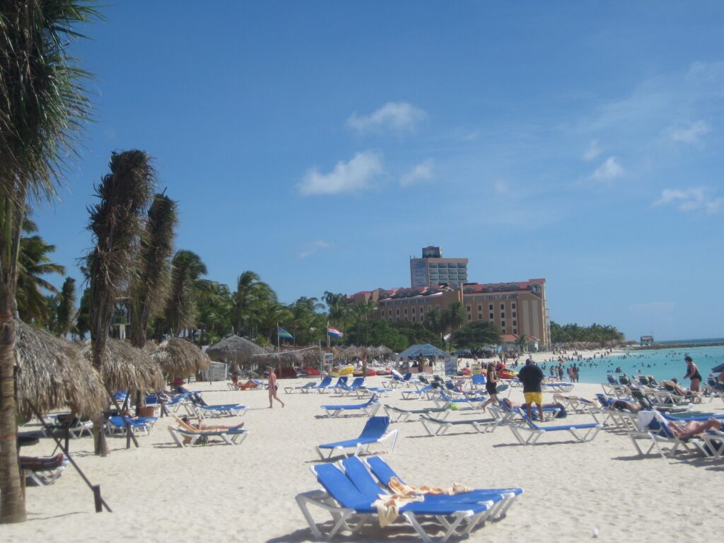 White sand beach, Palm Beach, Aruba with many loungers and people.