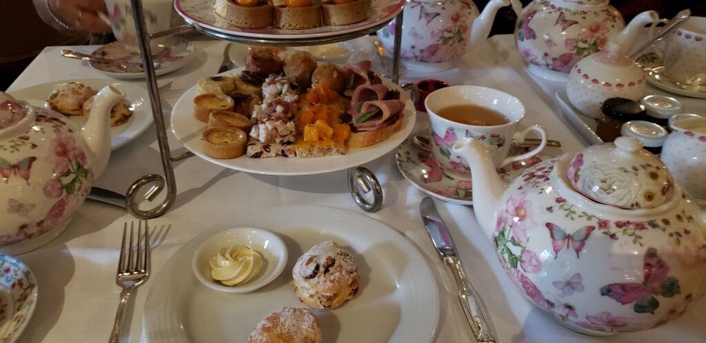 Afternoon tea setting of beautiful tea pots, scones and treats.