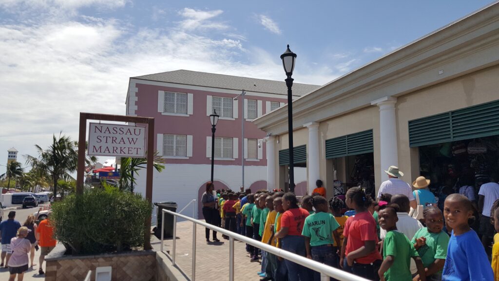 Nassau Straw Market with children and visitors at the entrance outside.