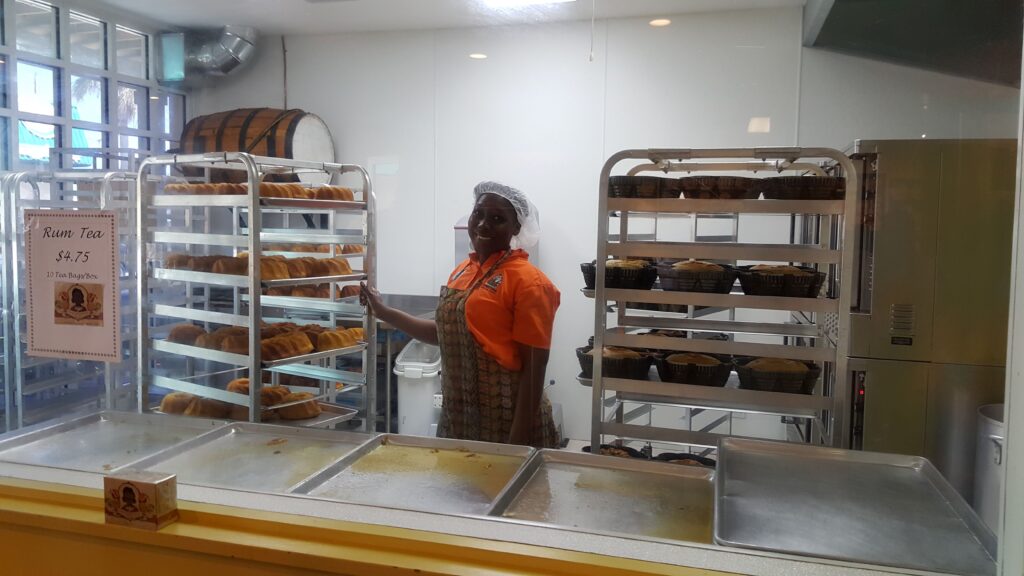 Bakery window in Tortuga store with woman smiling with freshly baked rum cakes.