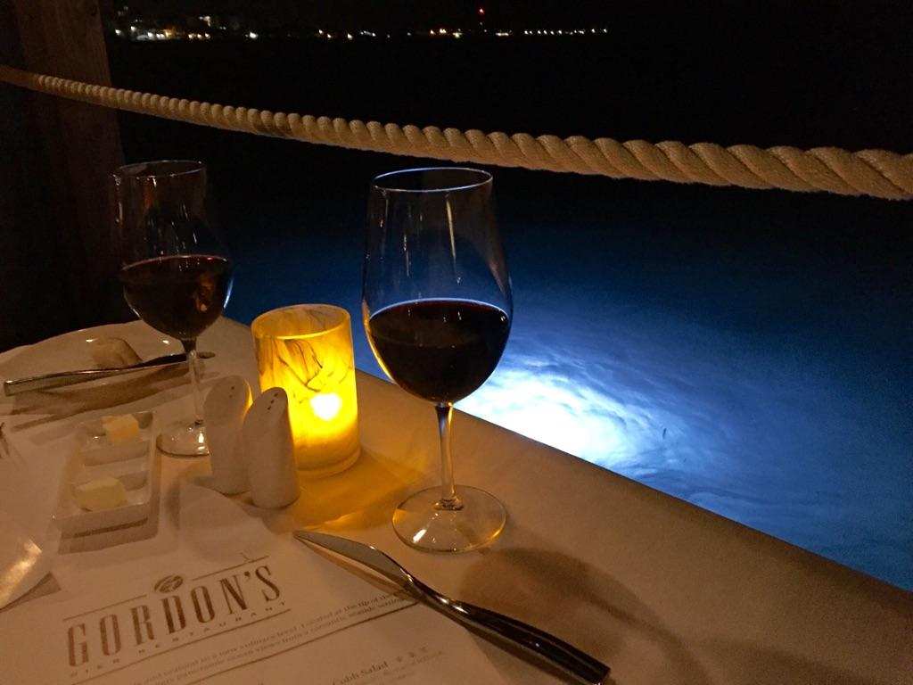 Candlelit table, with a glasses of wine, by the water on the pier at Gordon's restaurant at Sandals Royal Bahamian