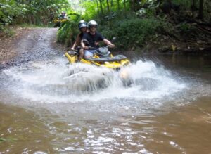 A couple on a yellow ATV going through water during excursion in Moorea.