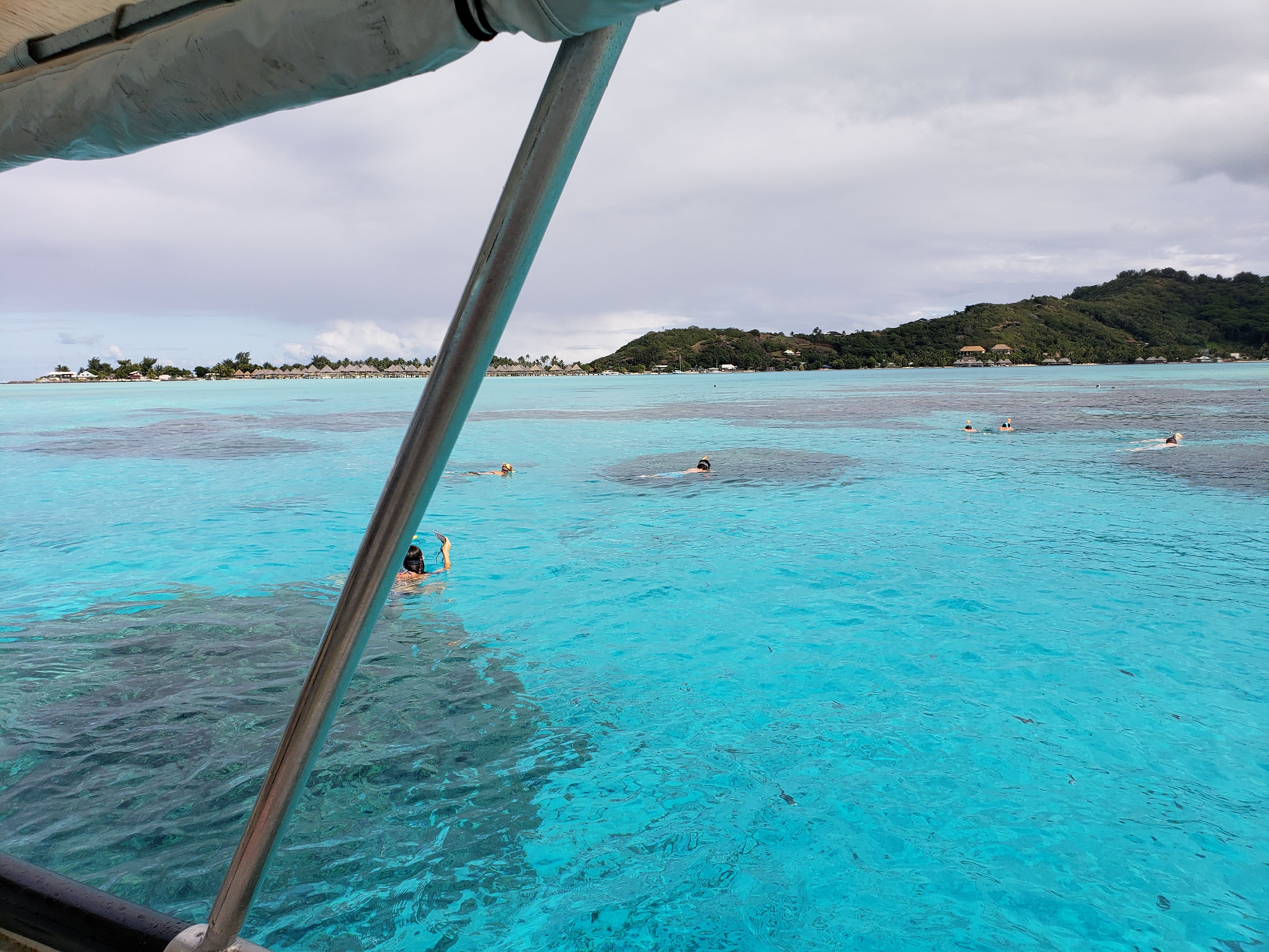 People snorkeling in beautiful clear blue waters of Bora Bora during excursion.