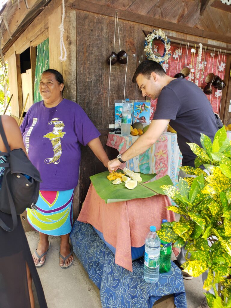 Man reaching for fruit sample on our visit to a family plantation in Bora Bora.