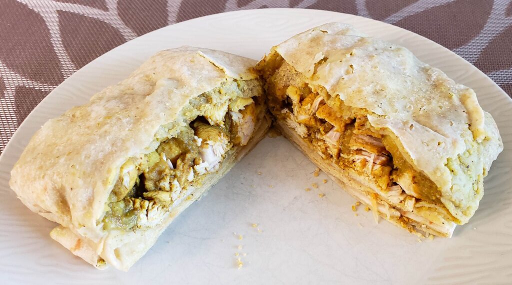 Roti cut in half from The Roti Hut, on a beige plate.