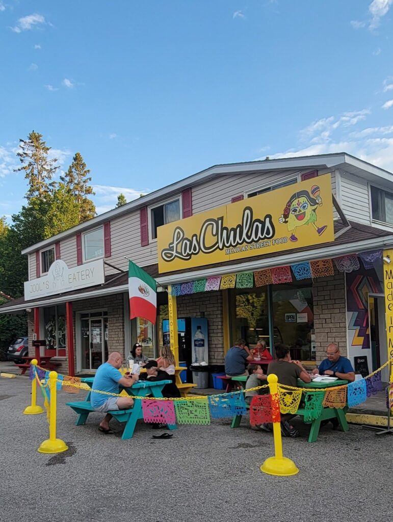 People eating on colorful picnic tables outside of Las Chulas in Tobermory