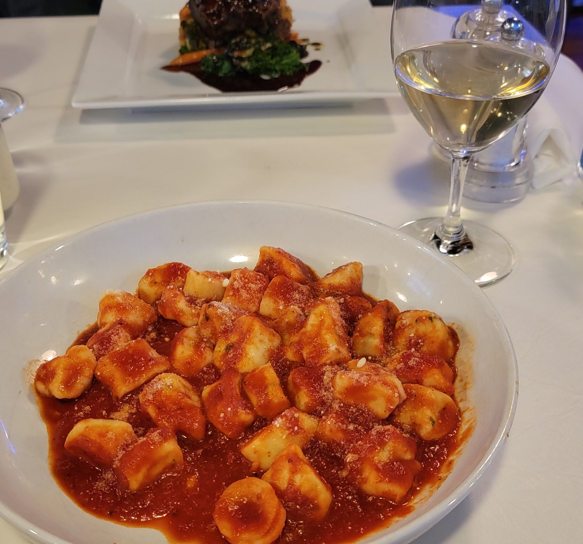 Ricotta gnocchi in tomato sauce from The Old Winery Restaurant in Niagara-on-the-Lake with a glass of white wine.