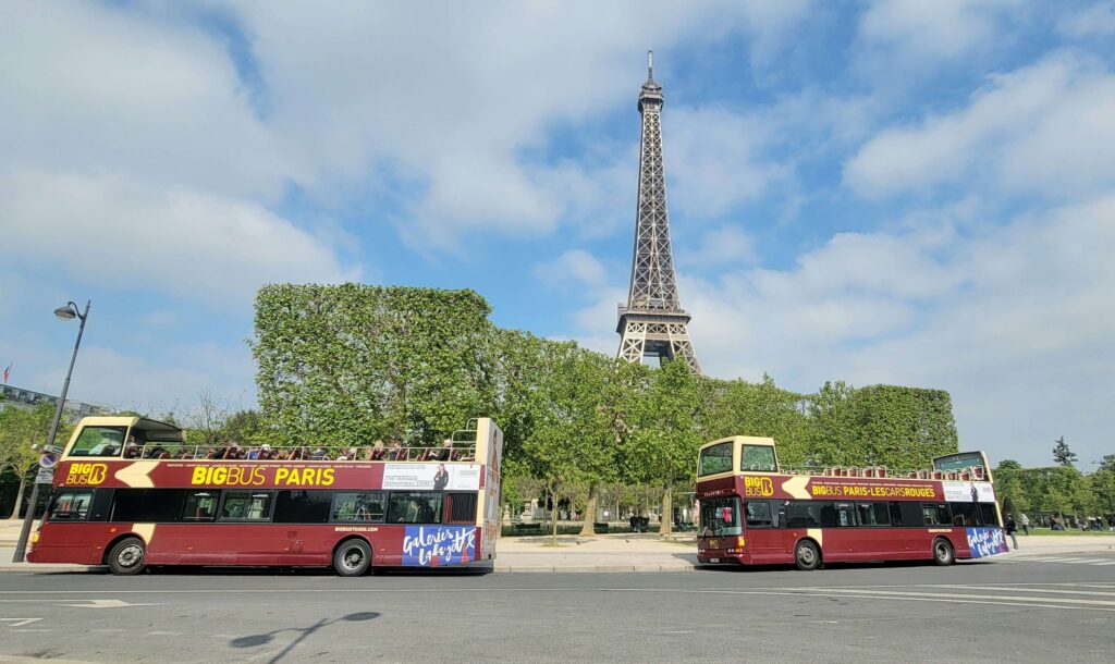 Two Big Bus Paris in parked in front of the Eiffel Tower.