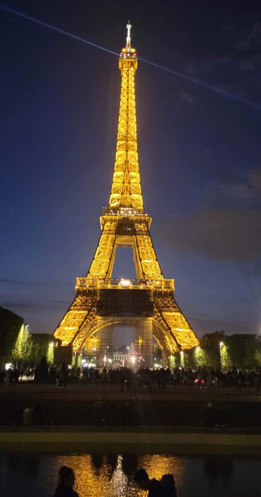 Eiffel Tower lit up in the evening from Champs de Mars.