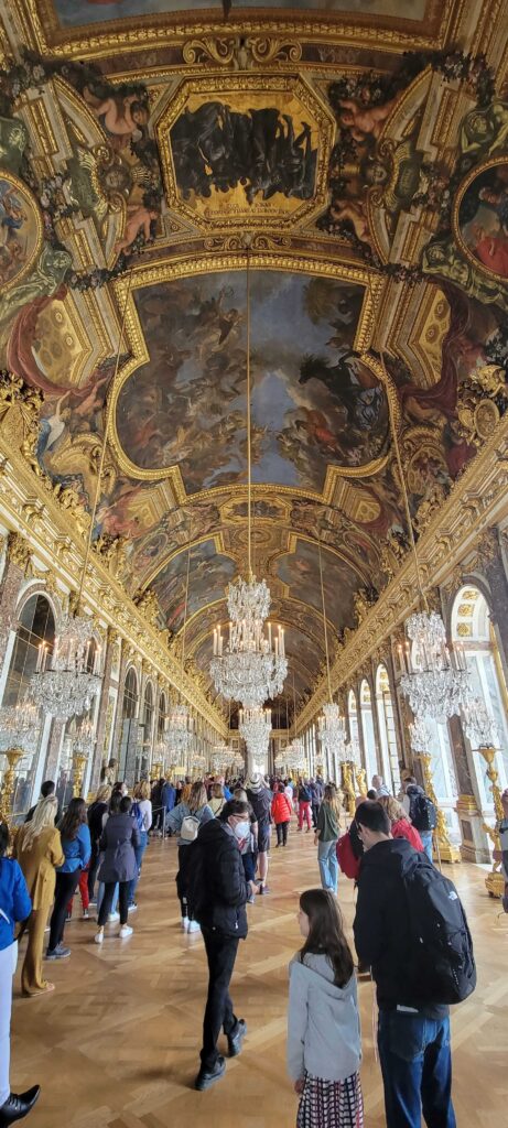 Many visitors and grand decor in the Hall of Mirros in the Palace of Versailles, France.