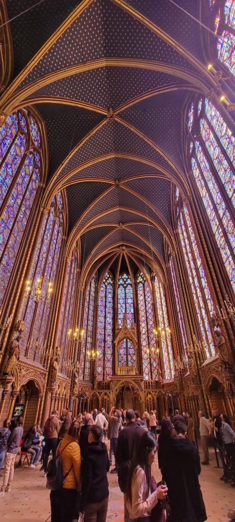 Beautiful high ceilings and stain glass windows inside Sainte Chapelle with visitors.