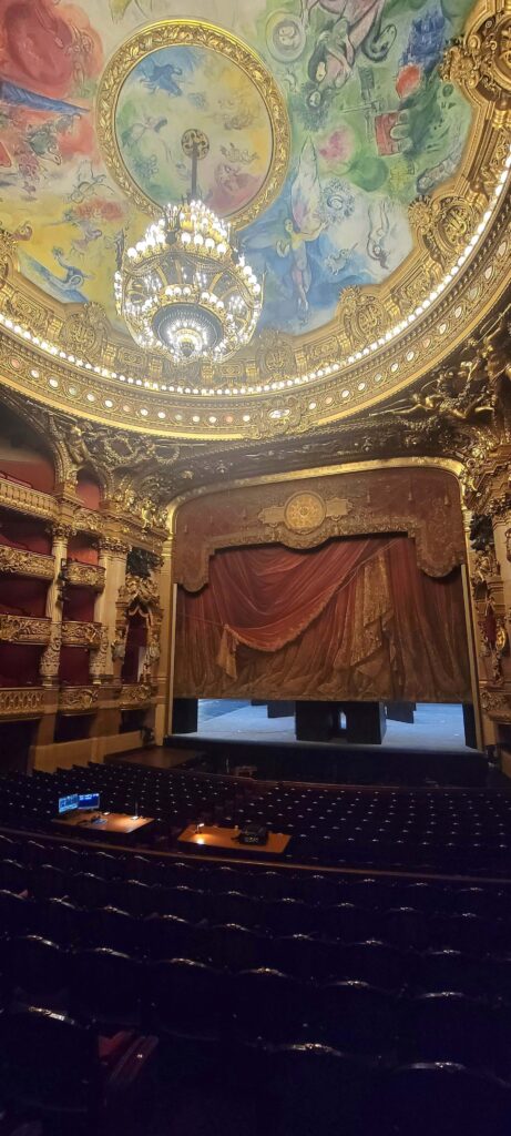 View of the beautiful, colourful ceiling and the stage and seating in Palais Garnier, Paris, France.