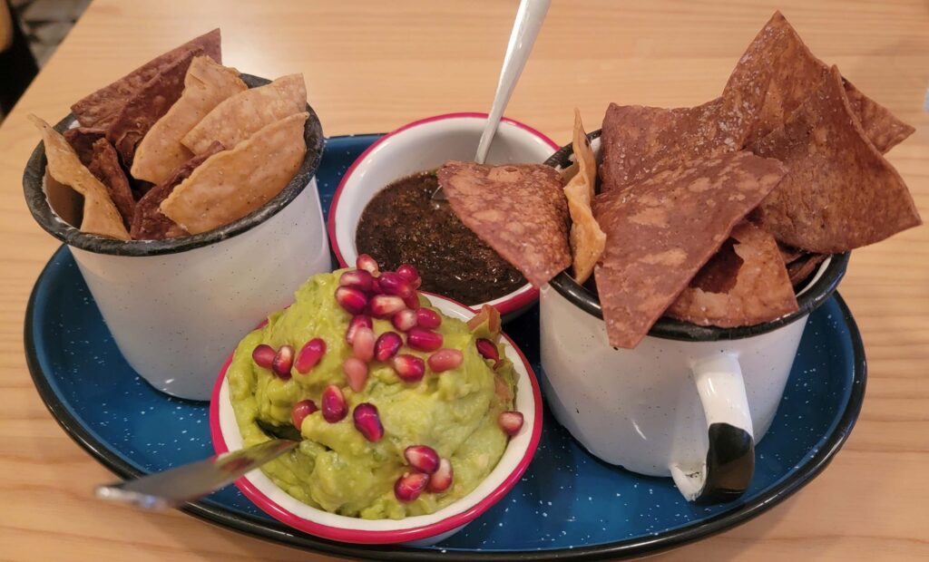 Chips served with guacamole with pomegranates on top, and house made sauce from Campechano
