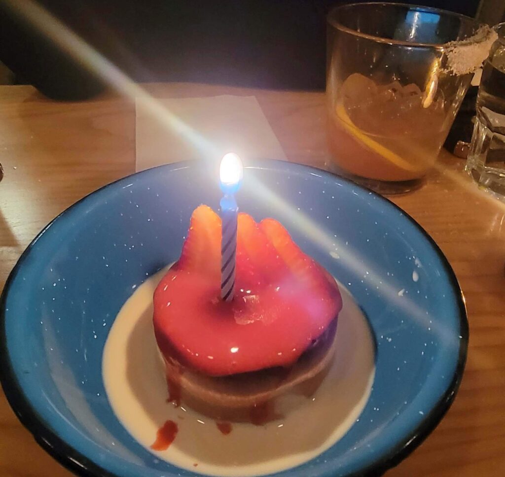 Dessert, Tres Leche, in a blue bowl with a lit blue candle, from Campechano.