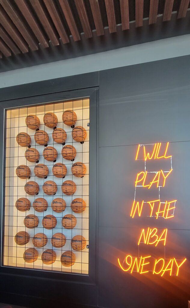 art display on the wall of basketballs and neon sign that says "I will play in the NBA one day"