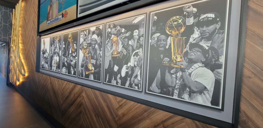 Six championship photos in black and white with the trophy in gold colour on the wall at the NBA Courtside Restaurant in Toronto.