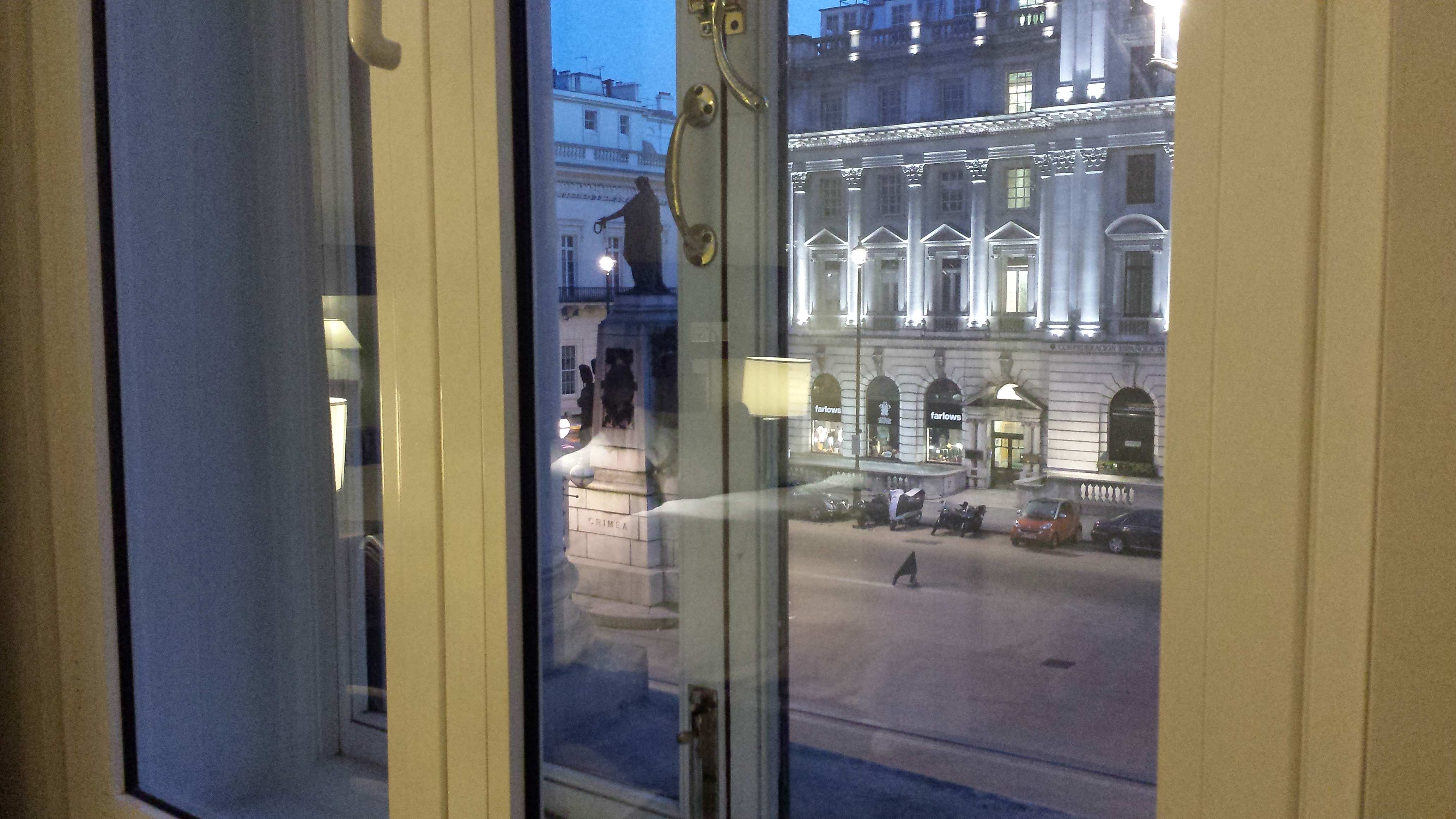 View of street, statue, and buildings outside of room.