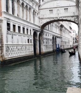 Outside view of the Bridge of Sighs with a gondola passing underneath.