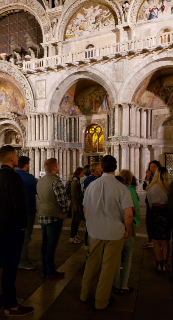 Small group outside gathered for Saint Mark's Basilica tour at night.