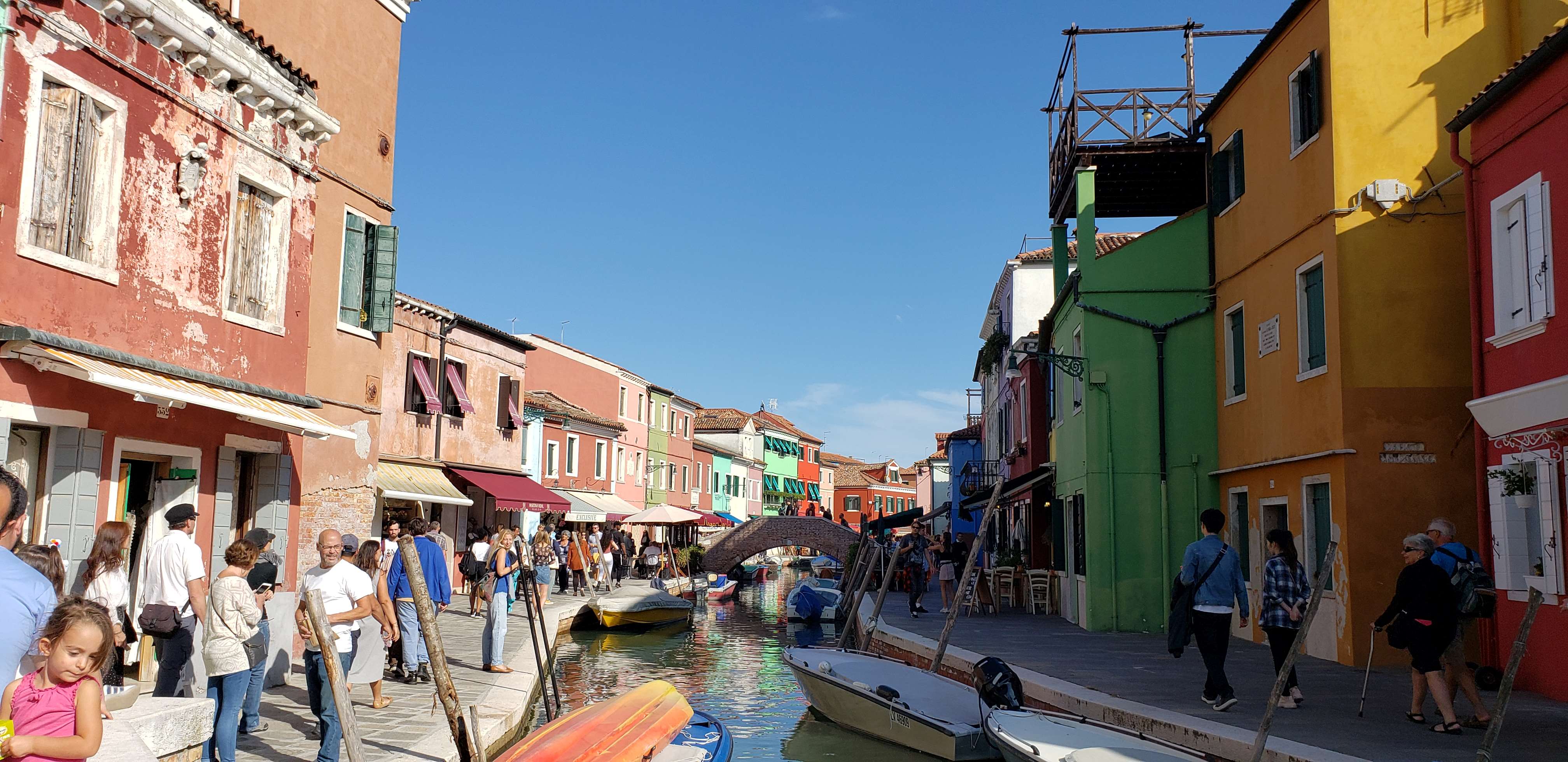 Colourful buildings and tourists exploring Burano.
