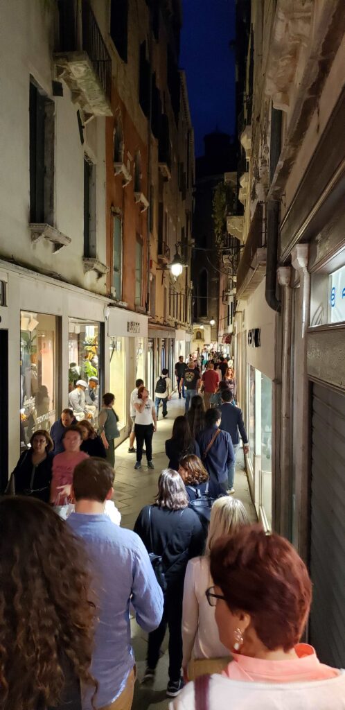 Lots of people walking through Merceria, the shopping area, in the evening, in Venice.