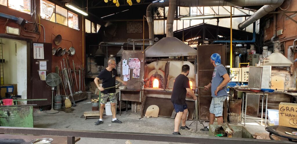 Three glassware makers in front of a furnace during a Murano Glass Factory tour in Venice.