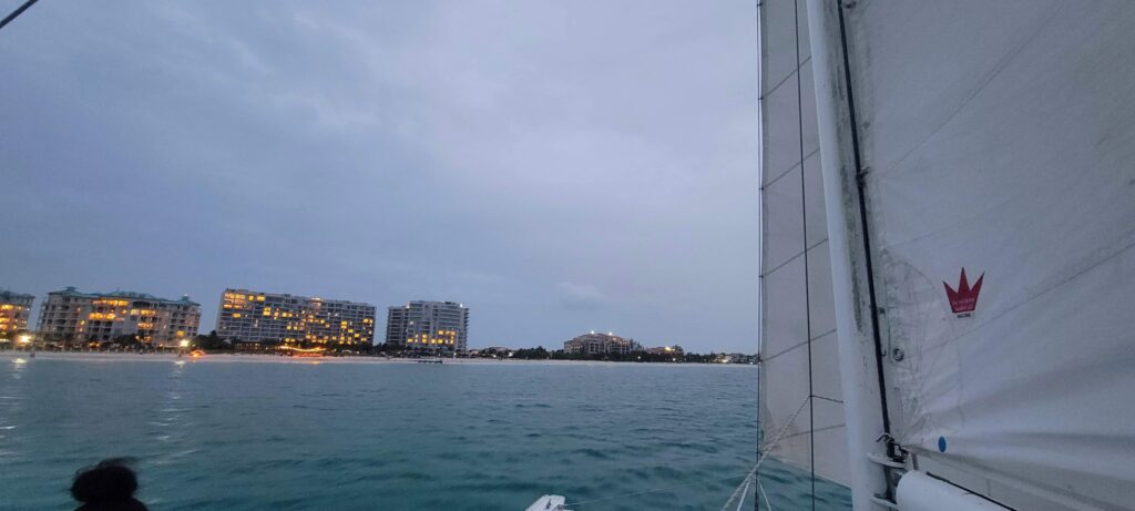 View of sail from the catamaran and hotels and homes lit up in Turks and Caicos.