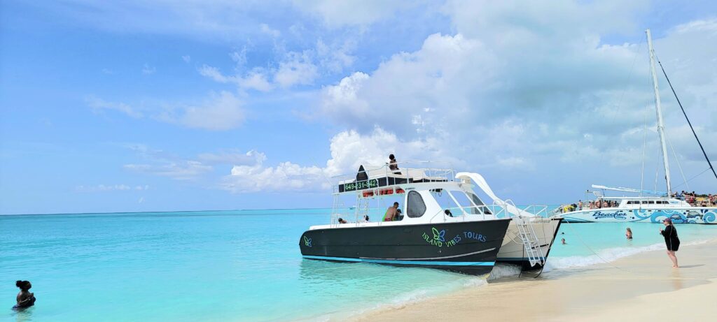 Boat docked in Turks and Caicos at Little Water Cay while people swim in the beautiful water.