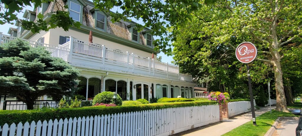 Exterior of Oban Inn in Niagara-on-the-Lake with white fence and surrounded by beautiful greenery on a sunny afternoon.