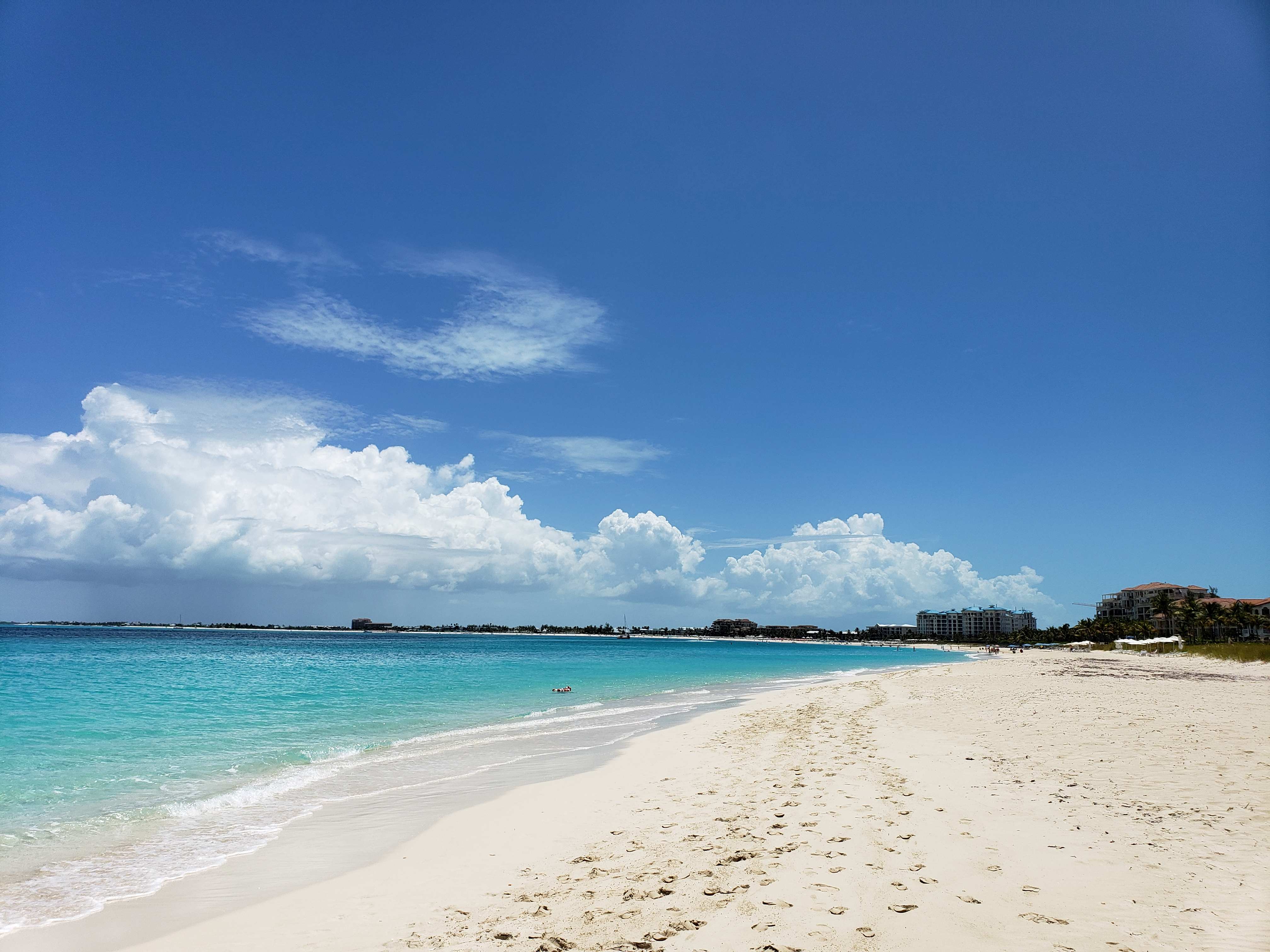 White sand beach and clear blue waters of Grace Bay Beach in Turks and Caicos on a sunny day.