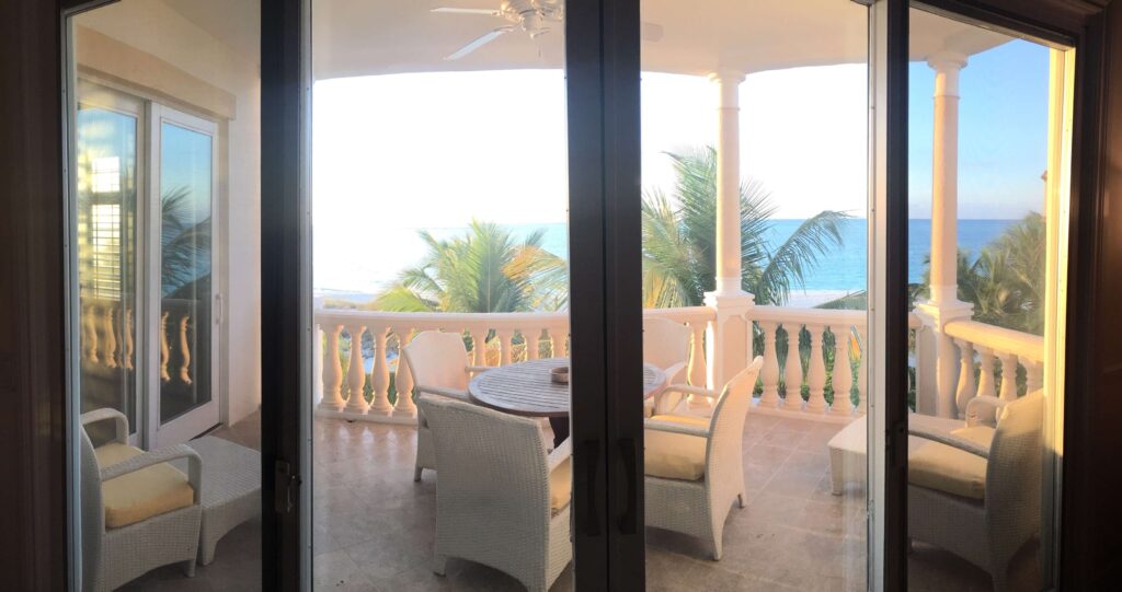 Terrace with white patio furniture, yellow cushions, and beautiful oceanfront view