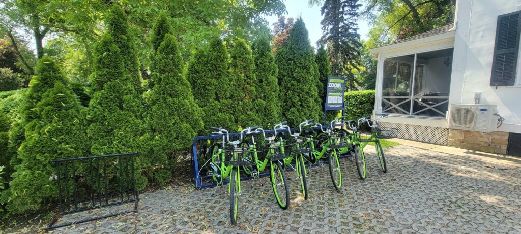 Six green bicycles that can be rented, located behind The Charles Hotel in Niagara-on-the-Lake.