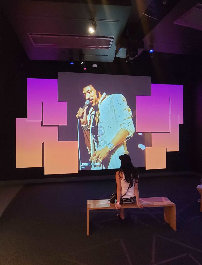 A woman on a bench watching a short film being shown in the National Museum of African American Music 