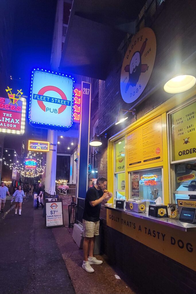 Eating a hot dog at night, outside the window at Daddy's Dogs in Printer's Alley in downtown Nashville.