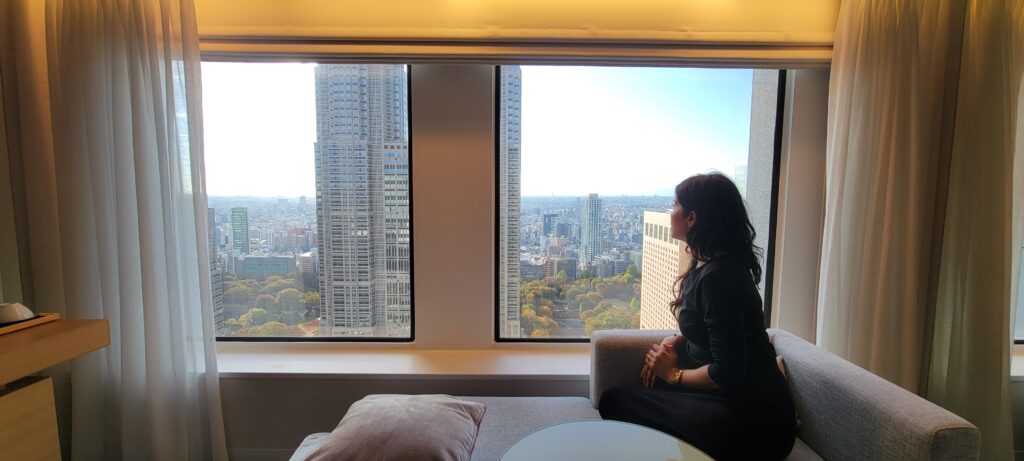 Woman sitting on couch looking at beautiful city view of Tokyo.