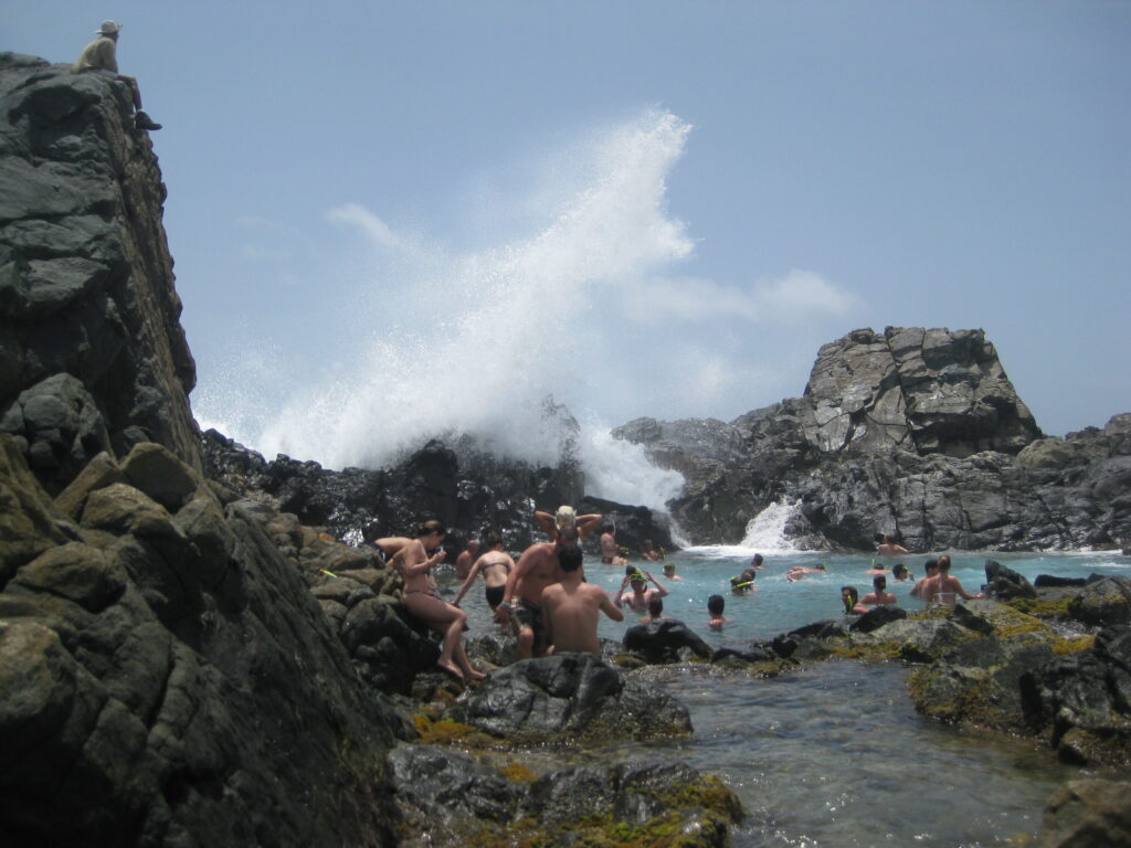 Many people enjoying the natural pool on a sunny afternoon during tour stop from our Aruba jeep tour.