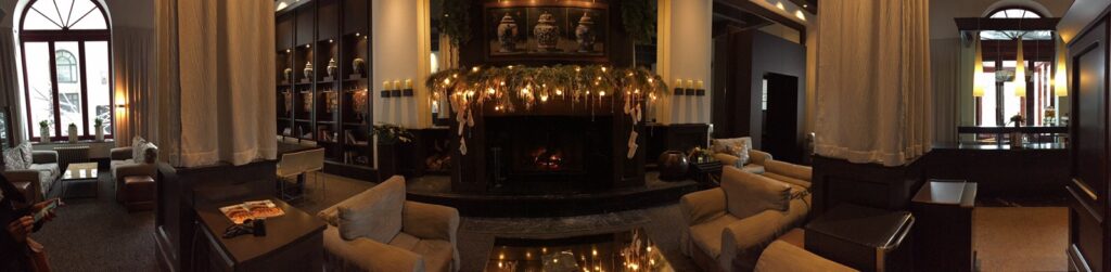 Panoramic view of elegant main floor and lounge at Hotel Le Germain Quebec with seating and decorated fireplace. 