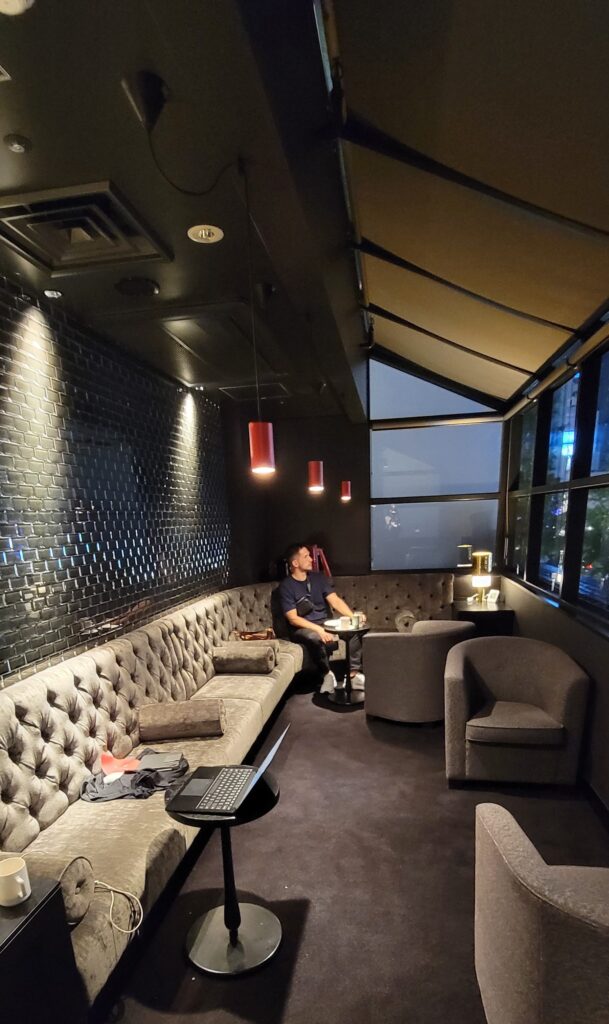 Additional comfortable seating area facing windows at the Cross Floor Lounge at the Cross Hotel Osaka.