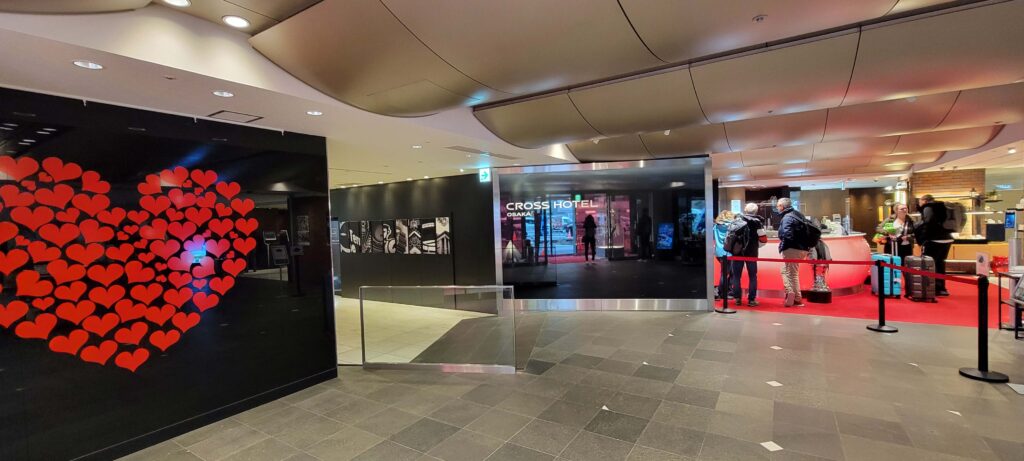 Part of the lobby of the Cross Hotel Osaka with large red heart artwork on one wall.