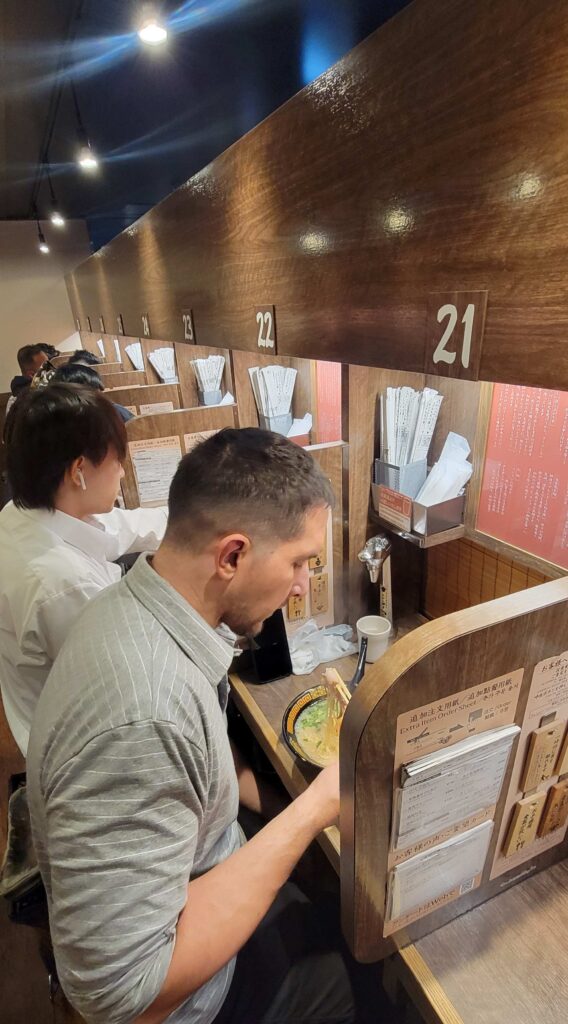 People eating ramen at Ichiran Ramen in Shinjuku in individual, numbered stalls.