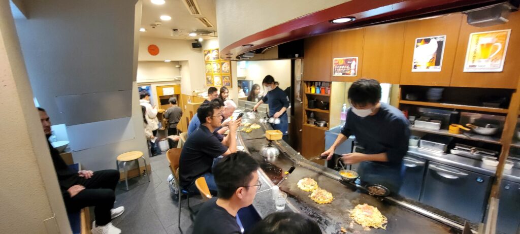 Interior and seating at Okonomiyaki Mizuno in Osaka on the main floor where customers watch their food cooked in front on them. 