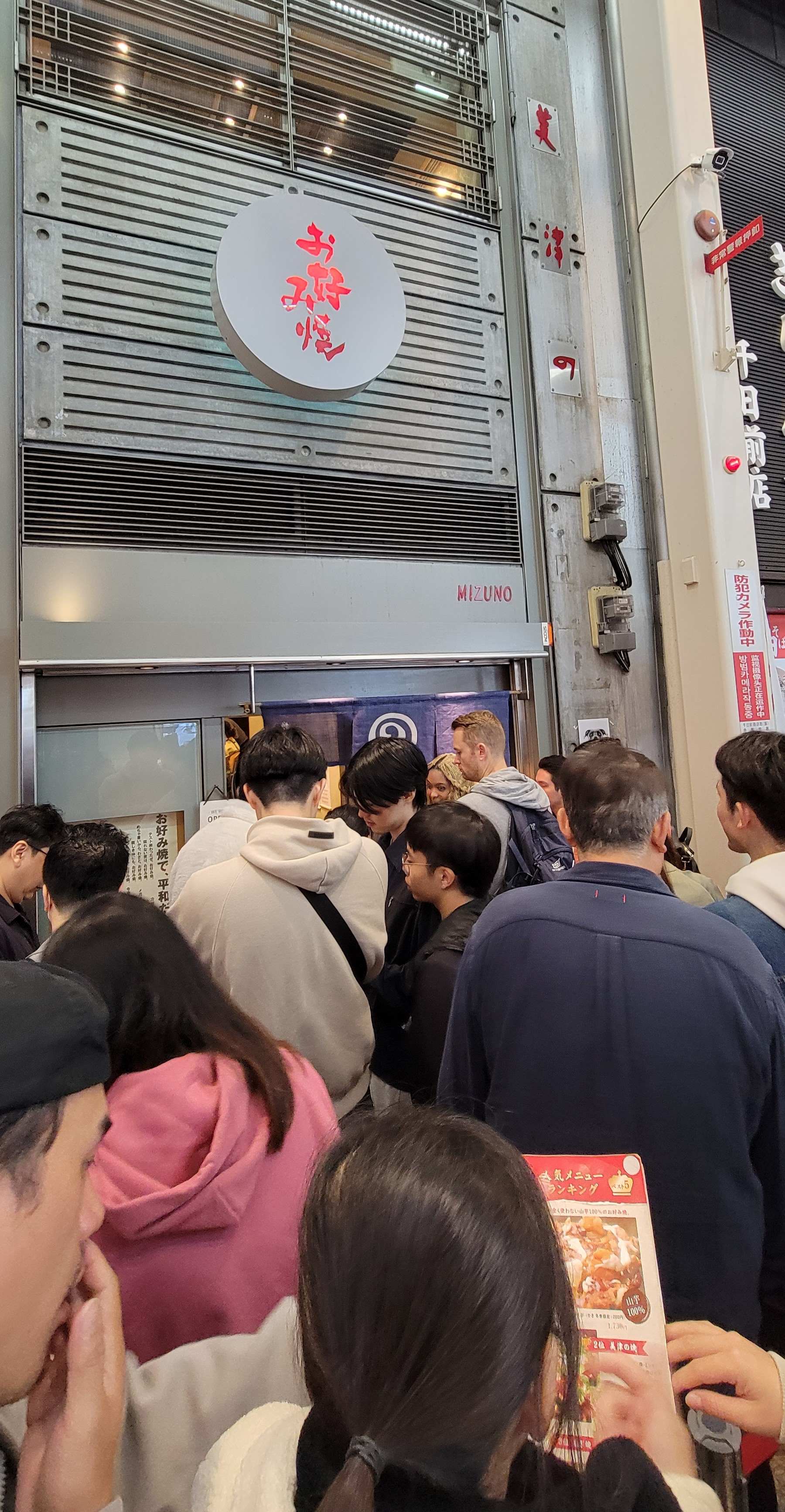 A woman looks at the menu while waiting in line outside Okonomiyaki Mizuno in Osaka.