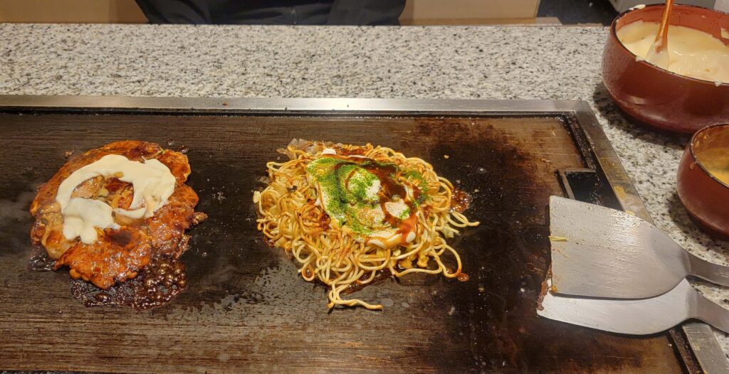 Two okonomiyaki being cooked on our table, at Okonomiyaki Mizuno restaurant in Osaka.