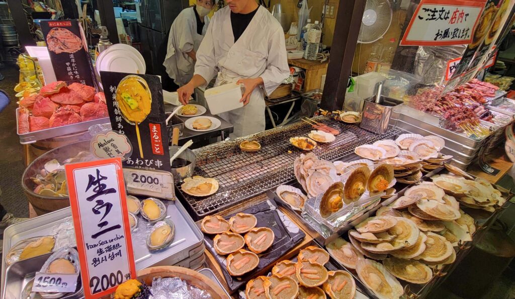 Storefront in Kyoto with seafood such as scallops, sea urchin, crabs, with small grill for cooking.