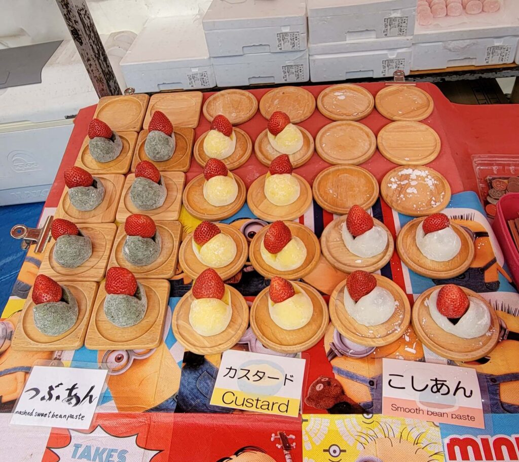 Three kinds of mochi with a strawberry on top, sold at a food stall in Kyoto.