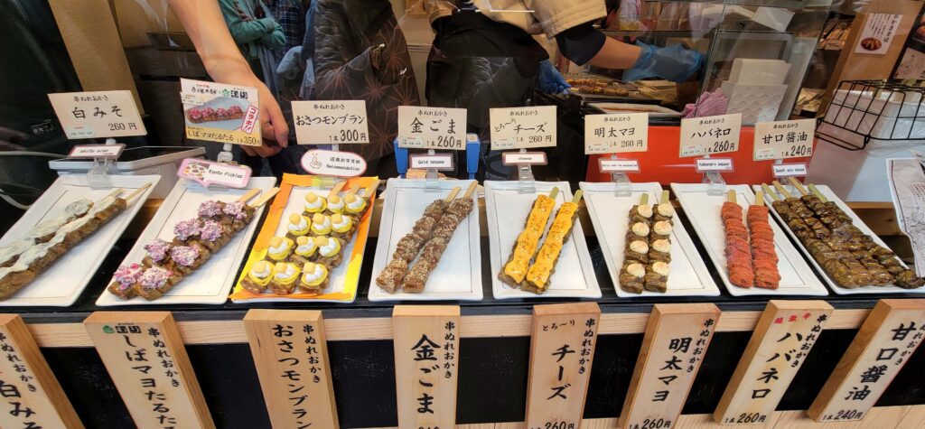 Variety of rice cake skewers with different toppings sold in food stall in Kiyomizu temple area in Kyoto.